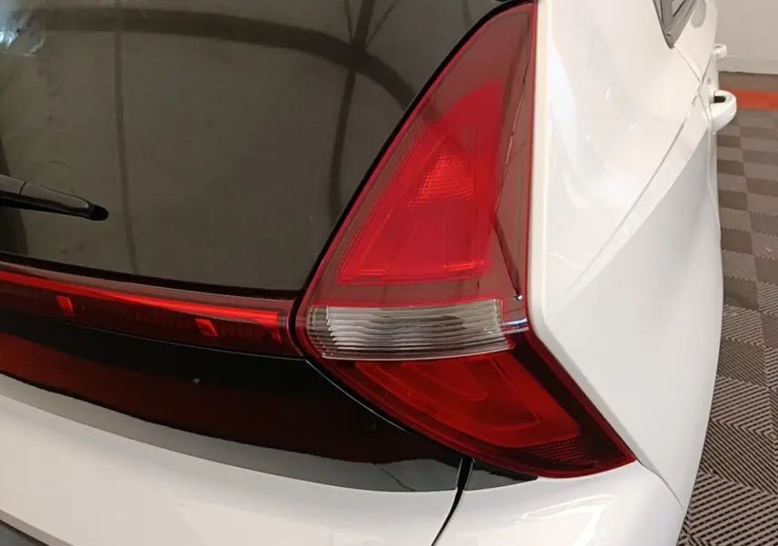 Gros plan sur le feu arrière droit rouge et blanc du Hyundai Bayon blanc, avec partie vitrée noire du coffre visible.