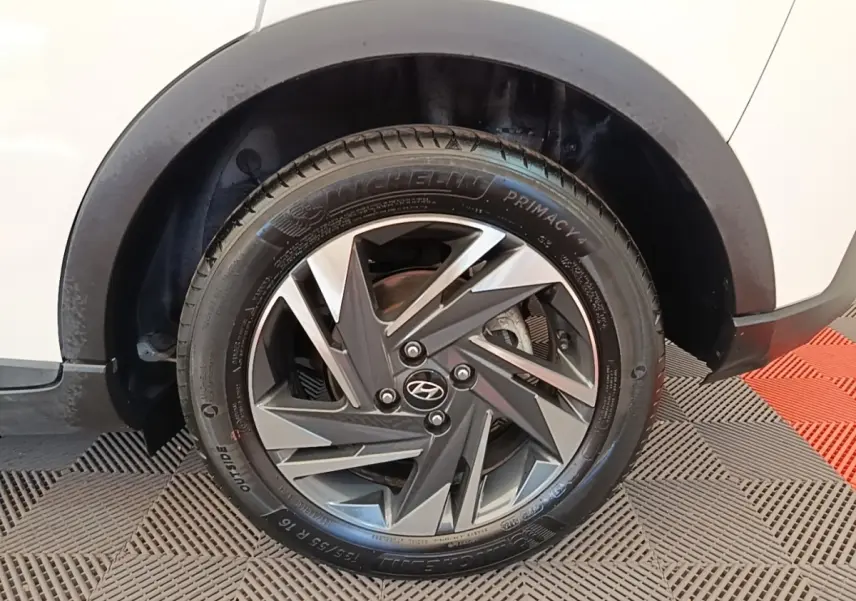 Gros plan sur la roue avant droite d'une Hyundai Bayon blanche, avec jante alliage au design géométrique bicolore.