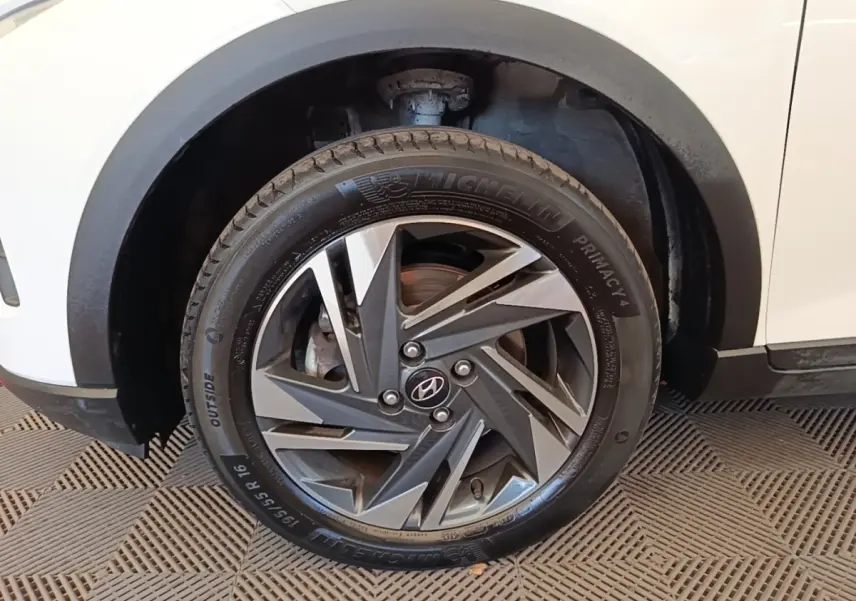 Gros plan sur la roue avant gauche d’une Hyundai Bayon blanche avec jante alliage au design géométrique.