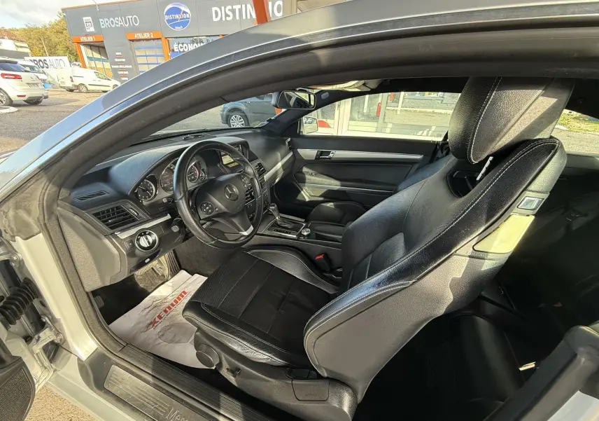 Intérieur noir cuir de la Mercedes Classe E 250 Coupé 2.2 CDI, vue côté gauche avec tableau de bord et volant visibles.