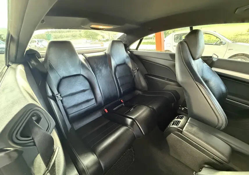 Vue intérieure arrière montrant les sièges en cuir noir d'une Mercedes Classe E 250 Coupé gris.