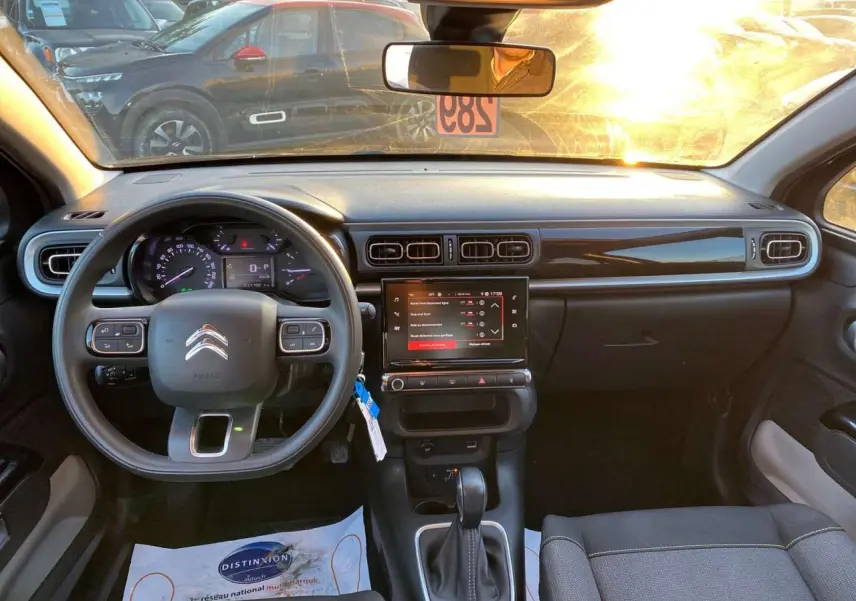 Vue intérieure avant du tableau de bord noir de la Citroën C3 Shine 2023 avec écran tactile et volant multifonction.