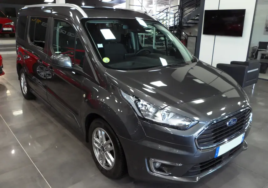 Ford Grand Tourneo Connect gris Magnetic en 3/4 avant droit dans un showroom lumineux avec jantes alliage.