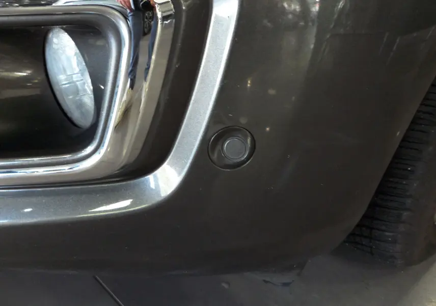 Gros plan sur le pare-chocs avant gris Magnetic du Ford Grand Tourneo Connect 2020 avec capteur de stationnement visible.