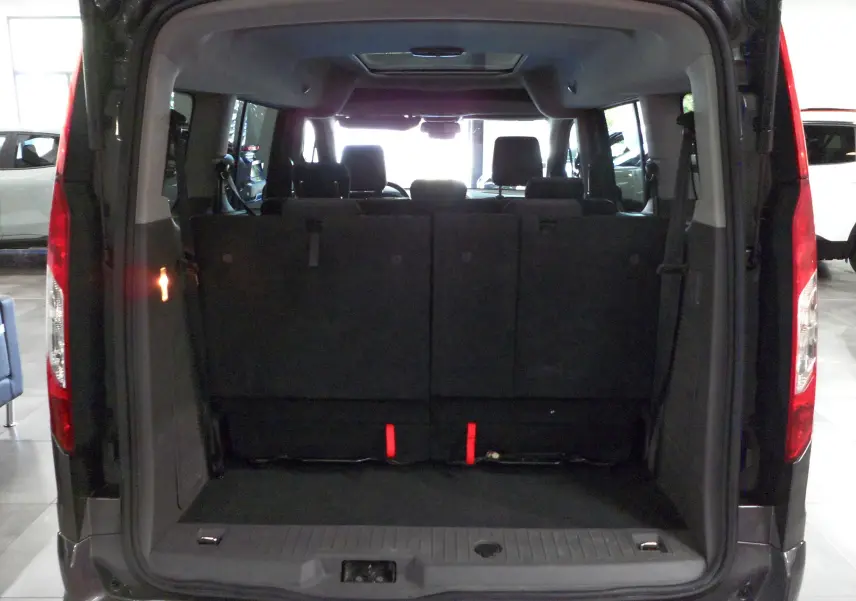 Vue arrière du Ford Grand Tourneo Connect gris Magnetic 2020 avec coffre ouvert et sièges rabattus visibles.