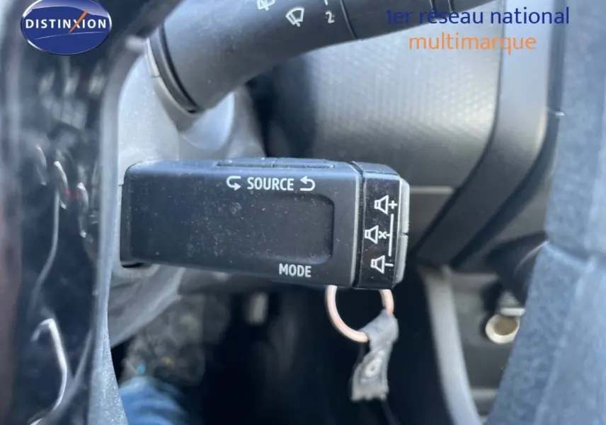 Gros plan sur la commande au volant de la Renault Clio blanche, avec bouton source et mode visible.