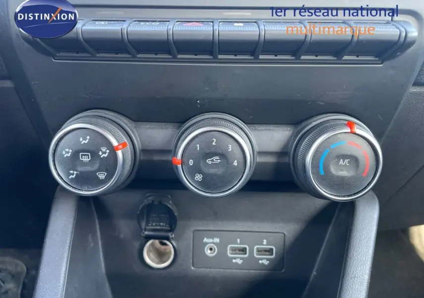Gros plan sur les commandes de climatisation et les ports USB du tableau de bord intérieur d'une Renault Clio blanche de 2020.