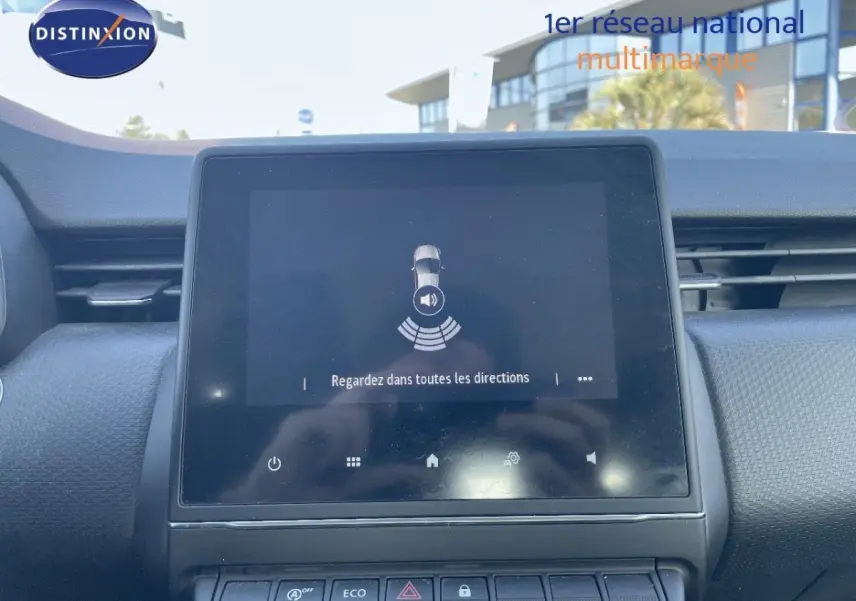 Écran tactile central allumé dans l'habitacle d'une Renault Clio blanche, vue de face du tableau de bord.