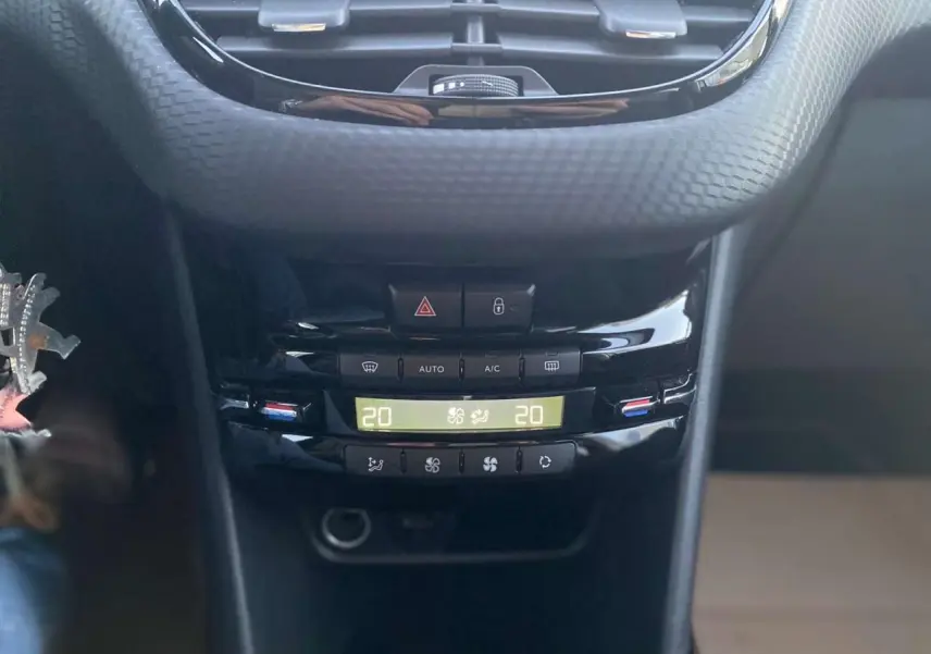 Vue rapprochée de la console centrale noire du Peugeot 2008 blanc GT Line, affichant la climatisation à 20 degrés.