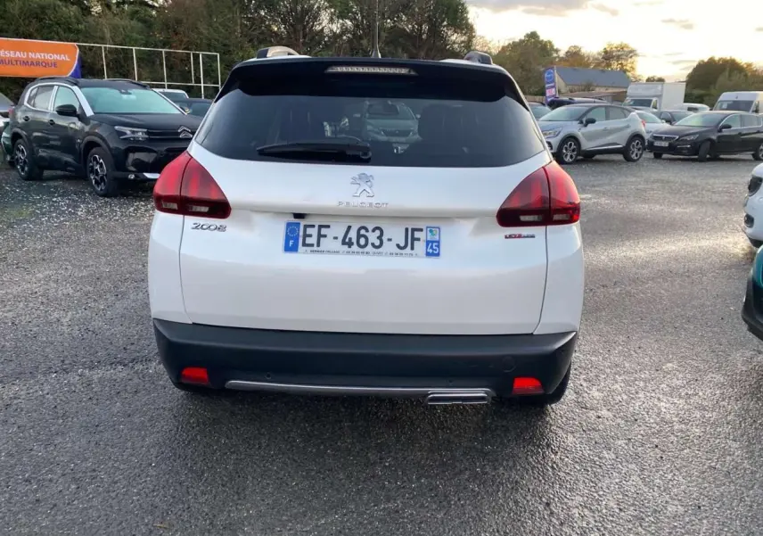 Vue arrière d'un Peugeot 2008 blanc GT Line de 2016 avec plaque d'immatriculation française visible sur un parking.