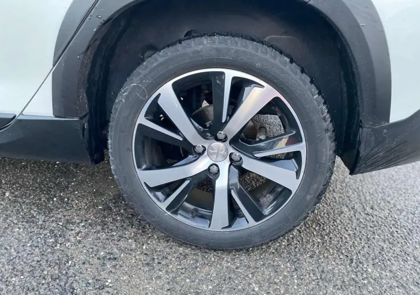 Gros plan sur la roue avant droite d'un Peugeot 2008 blanc 2016 avec jante alliage bicolore GT Line.