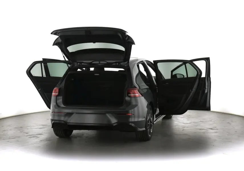 Volkswagen Golf VIII gris dauphin vue arrière avec portes et coffre ouverts dans un studio lumineux.