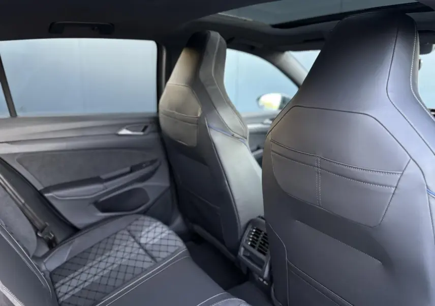 Vue intérieure arrière montrant les sièges sport en cuir noir et tissu gris de la Volkswagen Golf VIII R-Line.