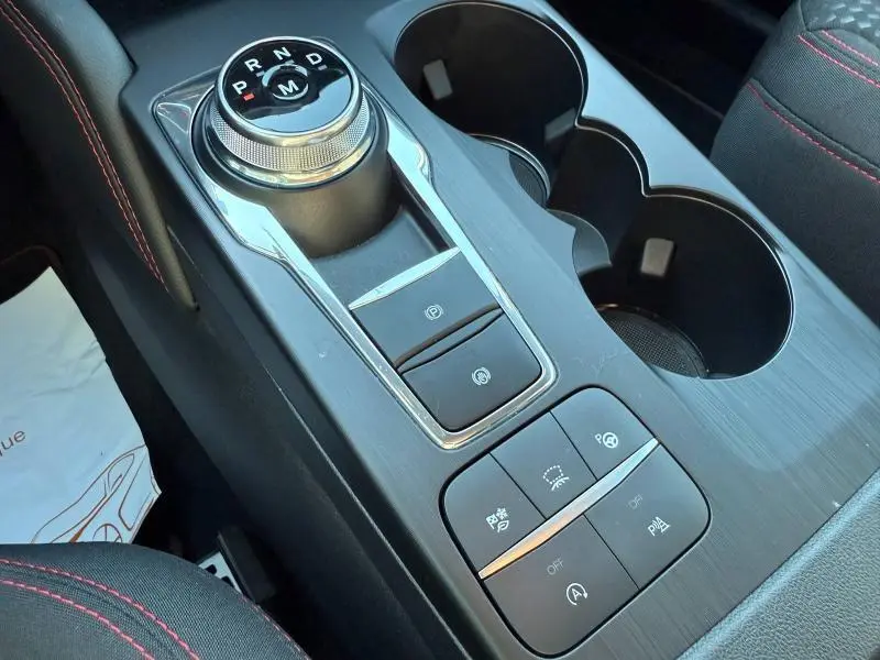 Vue rapprochée de la console centrale noire avec molette de sélection de vitesse et boutons de commande dans un Ford Kuga 2024.