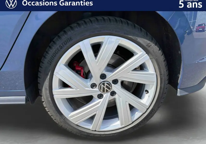 Gros plan sur la roue avant gauche d'une Volkswagen Golf 1.5 eHybrid bleue, jante alliage 17'' Richmond avec étrier de frein rouge.
