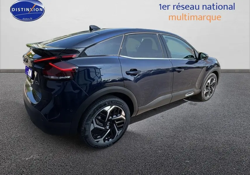 Vue 3/4 arrière droite d'une Citroën C4 bleu eclipse avec jantes alu et vitres surteintées sur fond neutre.