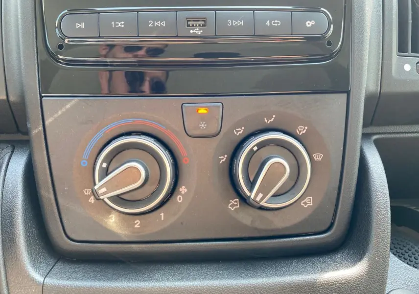 Tableau de bord du Citroën Jumper 2023 avec commandes manuelles de climatisation et lecteur multimédia noir.