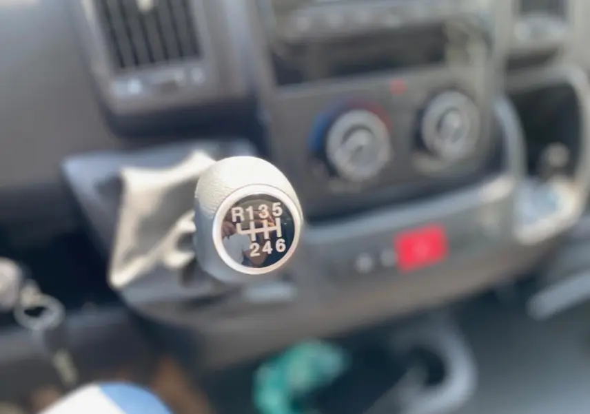 Le levier de vitesses manuel du Citroën Jumper 2023 en gros plan, avec le tableau de bord flou en arrière-plan.