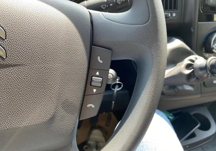 Gros plan sur le volant du Citroën Jumper blanc 2023, avec commandes téléphoniques et levier de vitesses manuel visible.