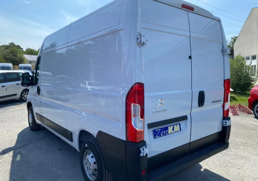 Vue 3/4 arrière droite du Citroën Jumper blanc 2023 avec portes arrière tôlées et plaque "Zéro KM" visible.