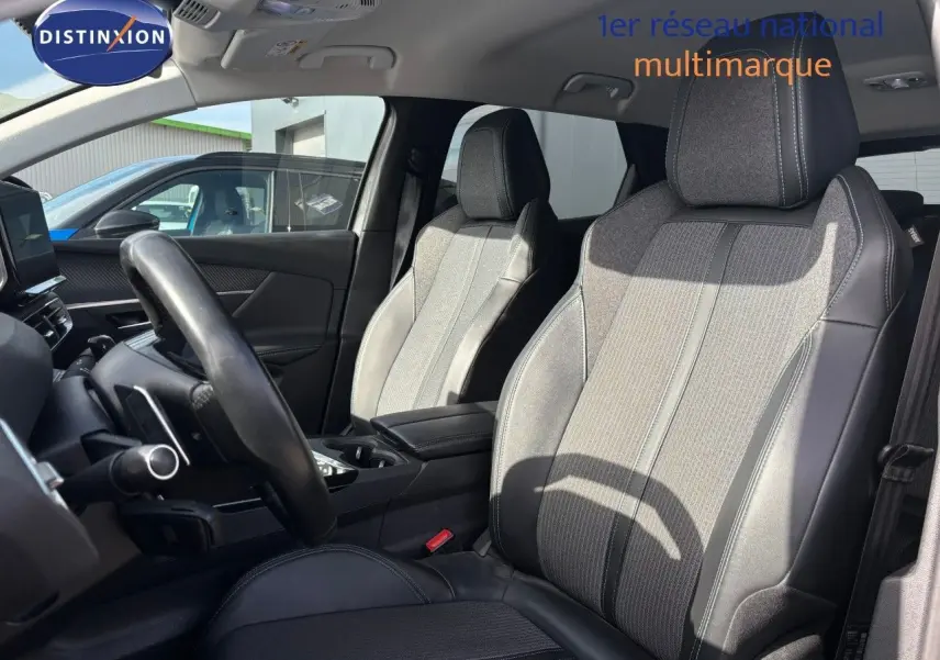 Intérieur du Peugeot 3008 hybride 2022, vue côté conducteur sur sièges en tissu et cuir gris avec volant noir.