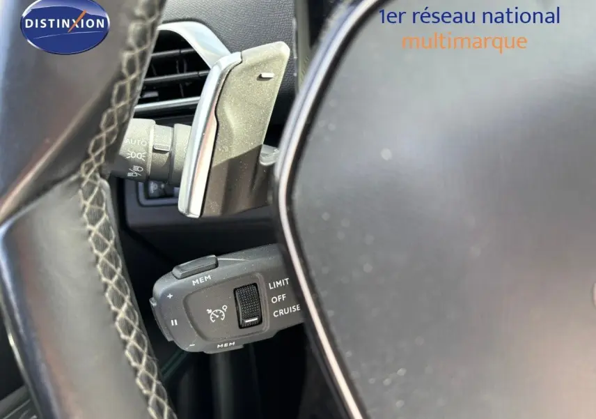 Gros plan sur la commande de régulateur de vitesse derrière le volant d'un Peugeot 3008 gris platinium.