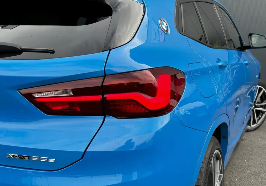 Vue 3/4 arrière droite d'une BMW X2 bleu Misano avec feux arrière LED et jantes alliage bicolores.
