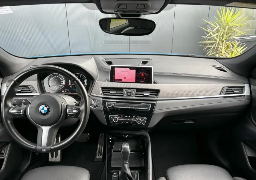 Vue intérieure avant du BMW X2 F39 M Sport 2021, tableau de bord noir avec écran GPS et volant cuir M.