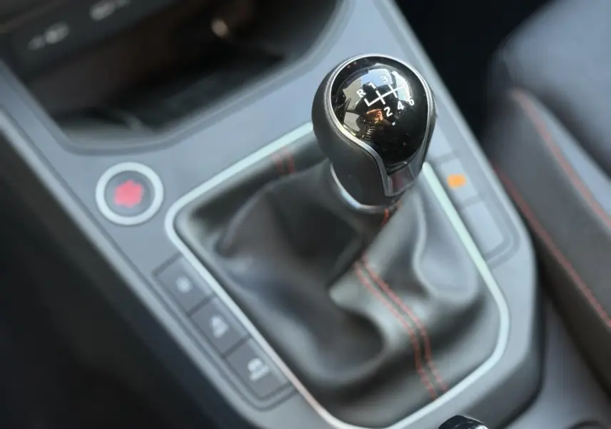 Gros plan sur le levier de vitesse manuel noir avec surpiqûres rouges de la SEAT Ibiza TSI 115 FR 2025.