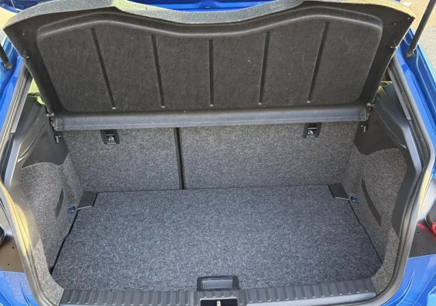 Coffre ouvert vu de l'arrière d'une SEAT IBIZA bleu saphir, montrant l'espace de chargement tapissé gris.