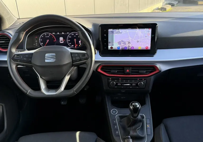 Vue intérieure frontale du tableau de bord de la SEAT Ibiza TSI 115 FR 2025 avec volant multifonction et écran tactile de navigation.