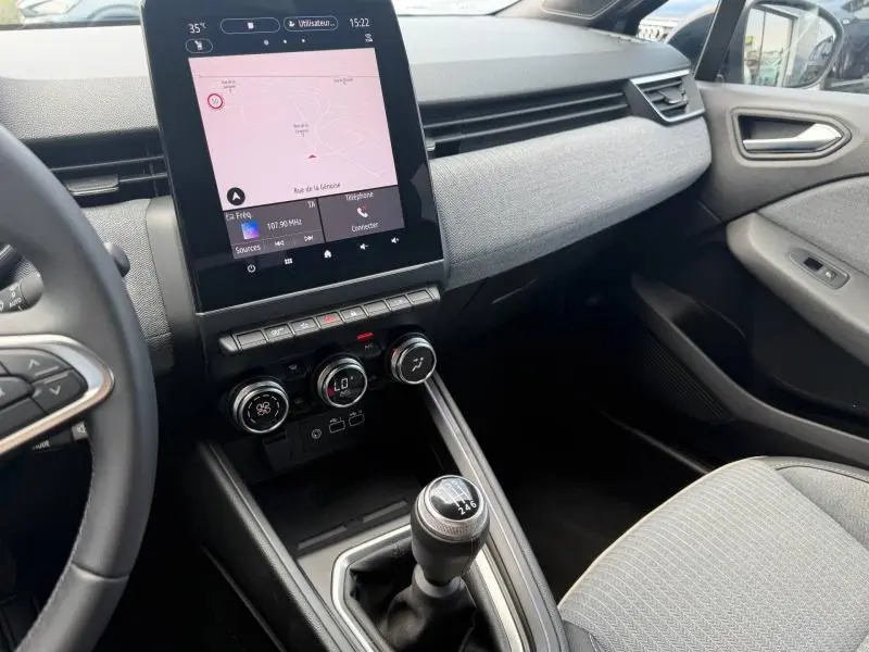 Intérieur de la Renault Clio gris schiste, vue côté passager avec écran tactile vertical et levier de vitesse manuel.