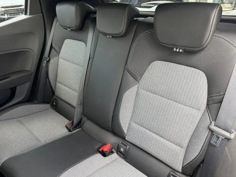 Vue rapprochée de la banquette arrière gris clair et noir de la Renault Clio 1.0 Eco-G 2025 avec ceintures et appuie-têtes.