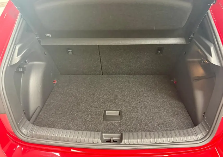 Coffre ouvert vu de l'arrière d'une Skoda Fabia rouge Velvet avec plancher plat et habillage intérieur noir.