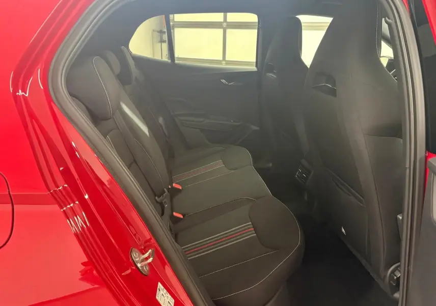 Vue intérieure côté gauche des sièges arrière noirs avec surpiqûres blanches et bandes rouges d'une Skoda Fabia rouge Velvet 2025.
