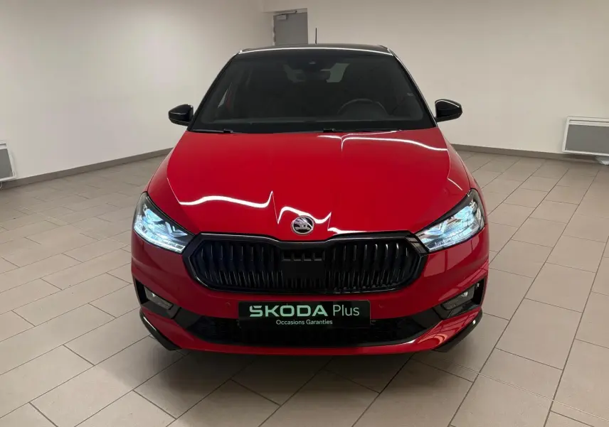 Vue frontale d'une Skoda Fabia 2025 rouge Velvet avec toit noir, phares allumés et calandre noire brillante.