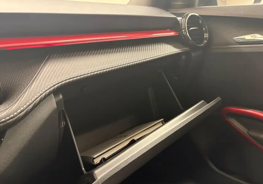 Vue intérieure côté passager de la boîte à gants ouverte d'une Skoda Fabia rouge velvet avec insert noir et détails rouges.