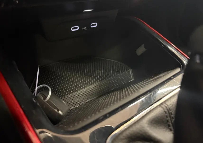 Gros plan sur la console centrale d’une Skoda Fabia rouge Velvet avec prise USB double et rangement intérieur noir.