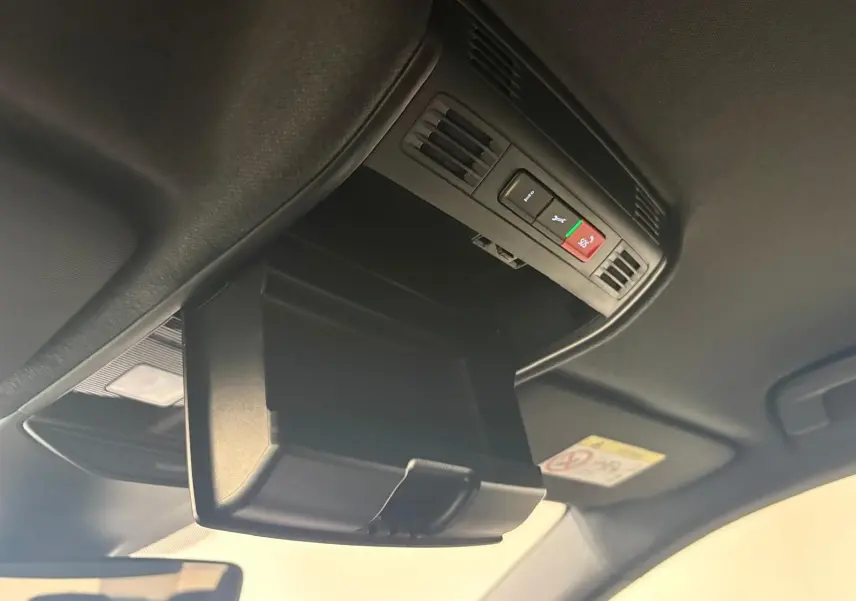 Gros plan sur le rangement plafond ouvert avec commandes d'assistance dans l'habitacle noir du Skoda Fabia 2025.