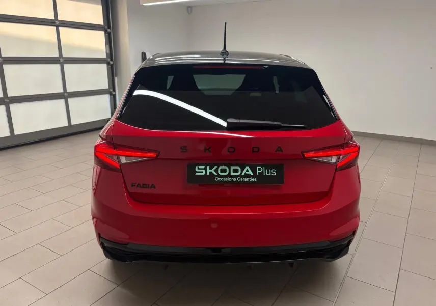 Vue arrière d'une Skoda Fabia 2025 rouge Velvet avec toit noir, en intérieur, mettant en valeur ses feux LED et son logo SKODA.