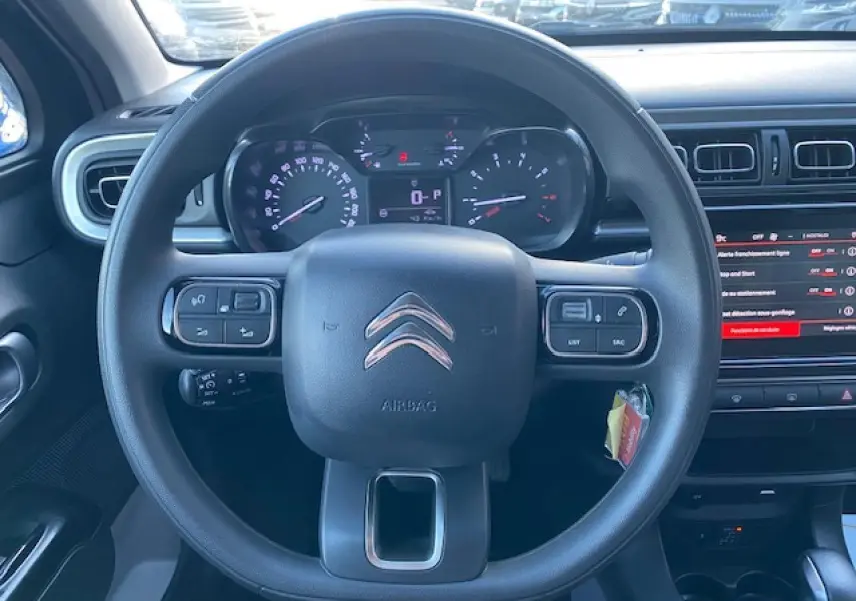 Vue rapprochée du volant et du tableau de bord d'une Citroën C3 Shine 2023 avec commandes intégrées et écran tactile.