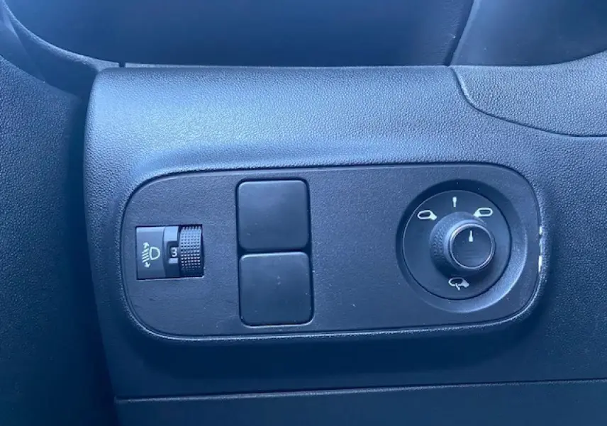 Vue rapprochée des commandes de réglage des rétroviseurs et des phares sur la porte côté gauche d'une Citroën C3 Shine noire toit rouge.