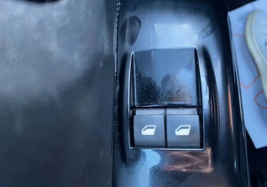 Gros plan sur les boutons de commande des vitres électriques côté conducteur d'une Citroën C3 Shine 2023 noir toit rouge.