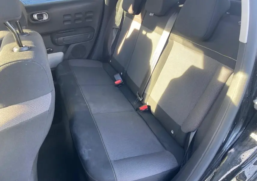 Banquette arrière noire vue côté droit de la Citroën C3 Shine 2023 avec portes ouvertes et ceintures visibles.