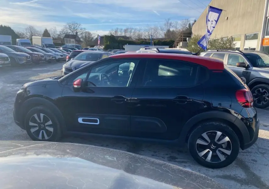 Profil côté gauche d'une Citroën C3 Shine 2023 noire avec toit rouge, jantes alliage diamantées et rétroviseurs rouges.