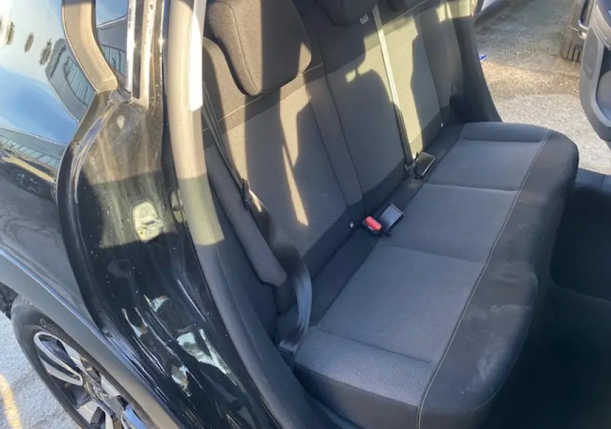 Vue côté gauche sur l'arrière d'une Citroën C3 2023 noire toit rouge, montrant la banquette arrière en tissu gris foncé.