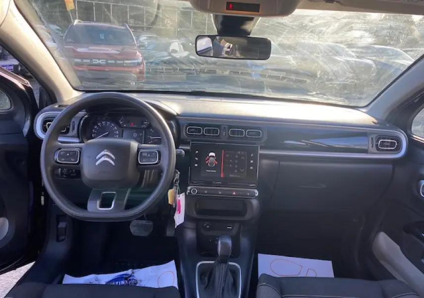 Vue intérieure avant de la Citroën C3 Shine 2023, tableau de bord noir avec écran tactile et volant multifonction.
