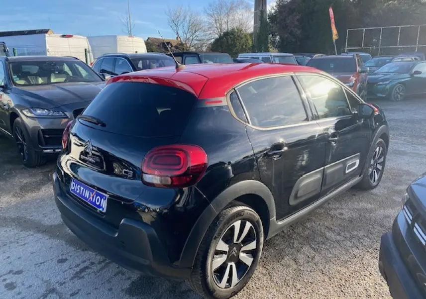 Citroën C3 Shine 2023 noir avec toit rouge, vue 3/4 arrière droit, jantes alliage et Airbump latéraux visibles.