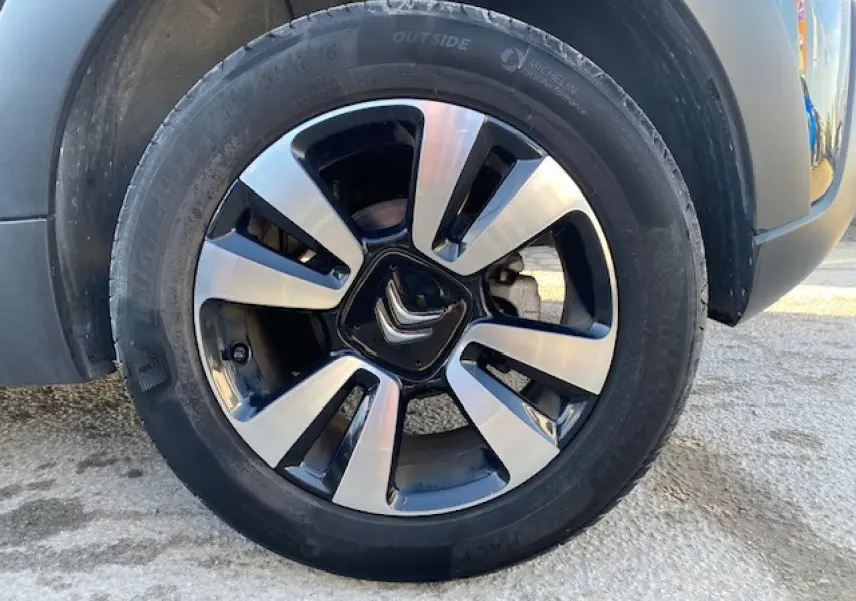 Gros plan sur la jante alliage diamantée 16 pouces noire et argentée d'une Citroën C3 Shine 2023 toit rouge.