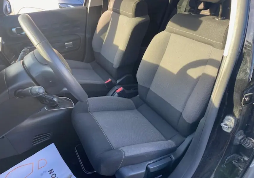 Vue intérieure côté conducteur de la Citroën C3 Shine 2023 avec sièges tissu gris et volant noir.